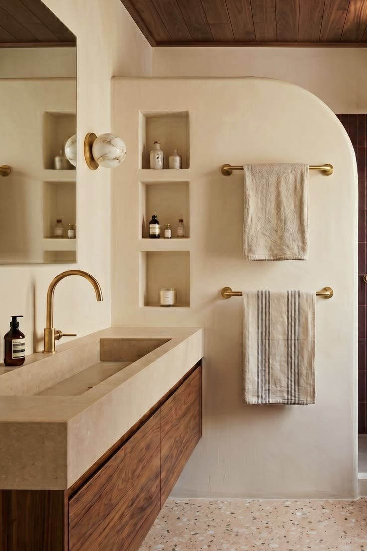 Salle de bain beige style spa avec niches en arche, vasque en pierre et robinetterie laiton brossé — ADJ Intérieurs Aix-en-Provence